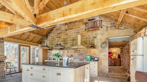 Una cocina con una isla central, paredes de piedra y techo de madera.