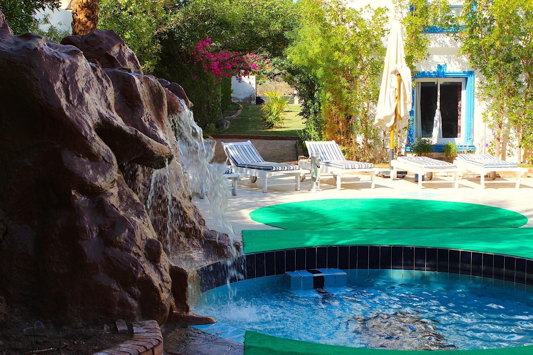 Ein Poolbereich mit Wasserfall, Liegestühlen und einem kleinen Pool.
