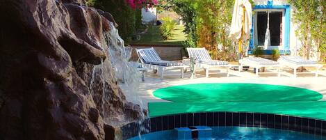 Ein Poolbereich mit Wasserfall, Liegestühlen und einem kleinen Pool.