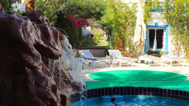 Un espace piscine agrémenté d’une cascade, de chaises longues et d’une petite piscine.