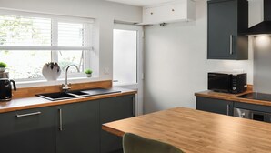 Een moderne keuken met een houten aanrecht, een spoelbak, een magnetron en een fornuis.