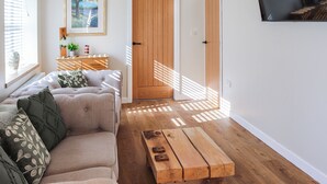 Een moderne woonkamer met een bank, een houten salontafel en een deur naar een andere kamer.