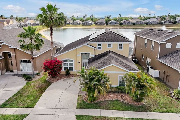 A residential area with houses, a lake, and palm trees.