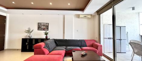 Una sala de estar moderna con un sofá modular, una mesa de centro y un amplio ventanal corredera que da a un espacio exterior.
