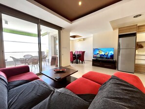 Una sala moderna con un sofá, una mesa de centro, un televisor y un comedor con sillas y una mesa.