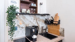 A compact kitchen with a marble backsplash, a coffee machine, a sink, and a wooden cutting board. - Apartment in Koblenz Near Deutsches Eck (Koblenz)