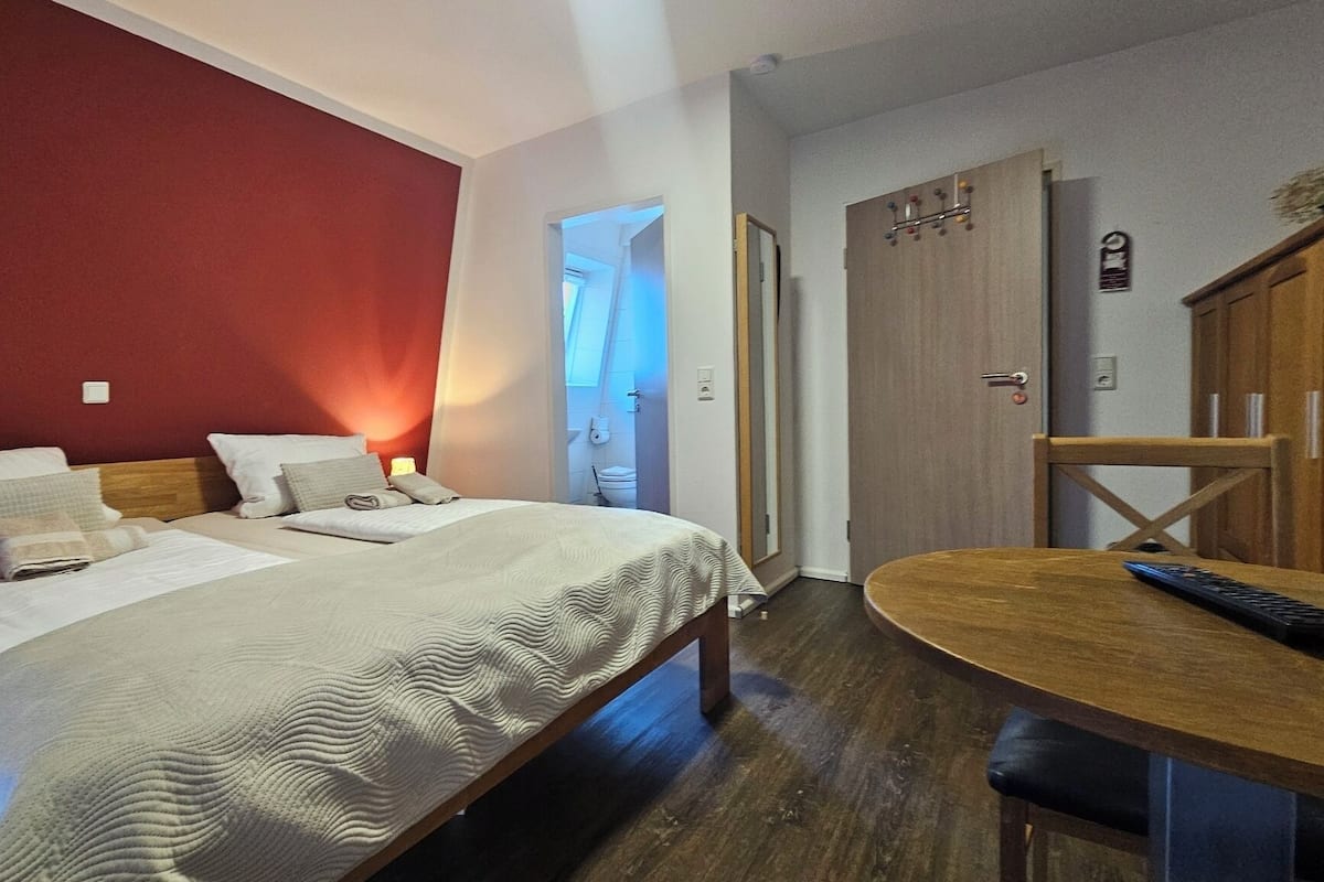 A hotel room with a bed, a desk, and a wardrobe.