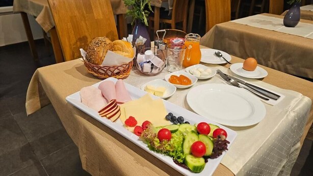 A breakfast table with a variety of food items including bread, cheese, fruits, and a salad. - Mondlicht Norddeich (Norden)