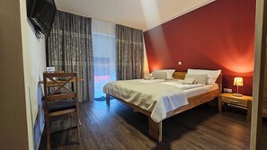 Een hotelkamer met een bed, een bureau, een stoel, een televisie en een raam met gordijnen.