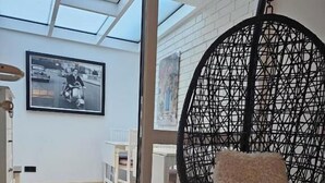 A modern interior with a hanging chair, a framed picture on the wall, and a view through a glass door. - Mondlicht Norddeich (Norden)