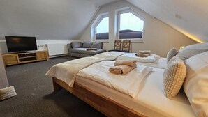 A bedroom with two beds, a TV, a sofa, and a window. - Mondlicht Norddeich (Norden)