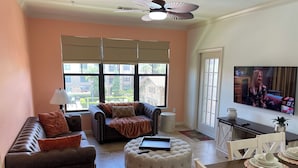A living room with a sofa, ottoman, and a dining area with chairs and a table.