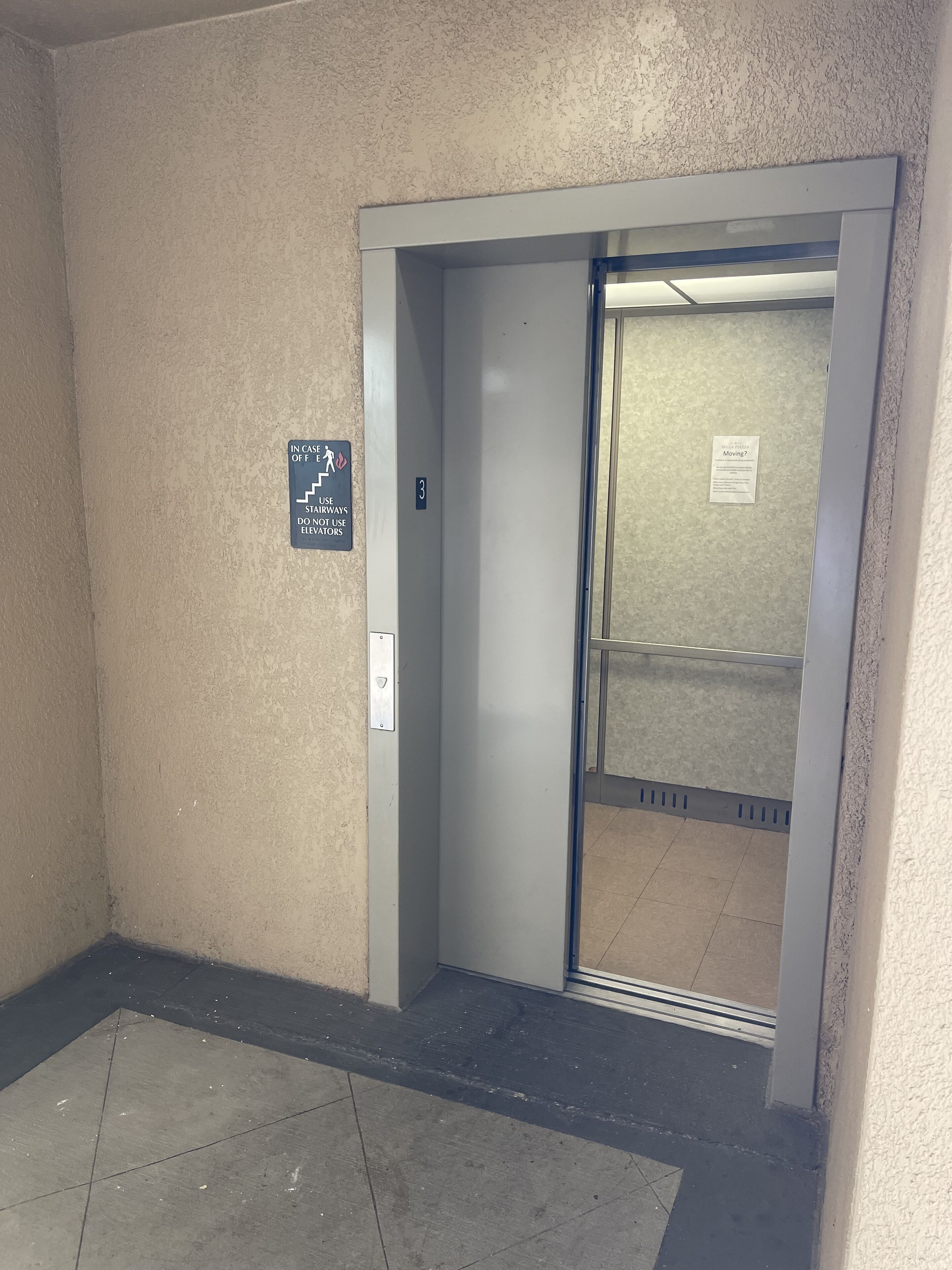 An elevator with a sign indicating the use of stairways in case of fire, and a number 3 sign on the wall.