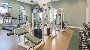 A gym with treadmills, weight machines, and dumbbells.