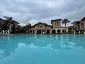 Ein Schwimmbecken mit einem Steinhaus im Hintergrund.