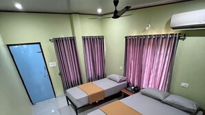 Une chambre d’hôtel avec deux lits, un ventilateur de plafond et un appareil de climatisation.