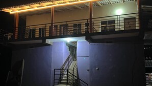 Un bâtiment doté d’un escalier menant à un balcon, le tout entouré d’une zone délimitée par une clôture.