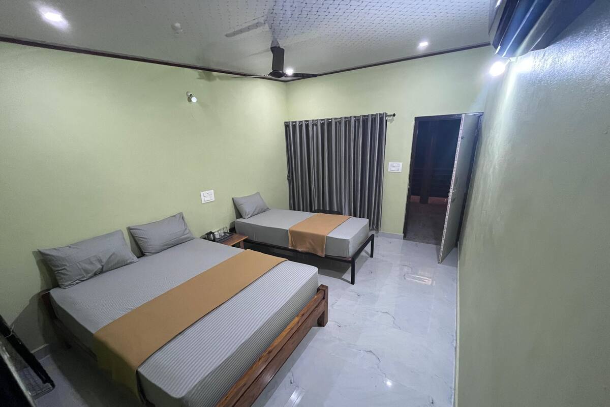 A room with two beds, a ceiling fan, and a door leading outside.