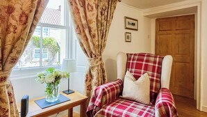 A cozy room with a plaid chair, a small table with a lamp, and a window with curtains. - The Old Baron's Courthouse (Ceres, near St Andrews)