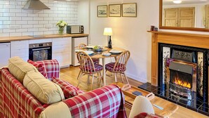 A cozy living room with a sofa, chairs, a fireplace, and a dining area with a table and chairs. - The Old Baron's Courthouse (Ceres, near St Andrews)