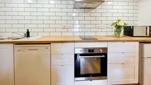 A modern kitchen with white cabinetry, a dishwasher, an oven, and a microwave. - The Old Baron's Courthouse (Ceres, near St Andrews)