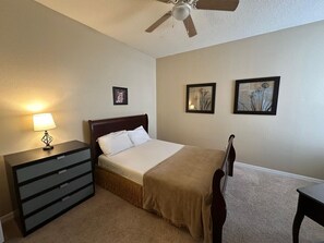 A bedroom with a bed, a dresser, a chair, and a ceiling fan. - Disney 3BR Home, Pool, Lake View (Kissimmee)
