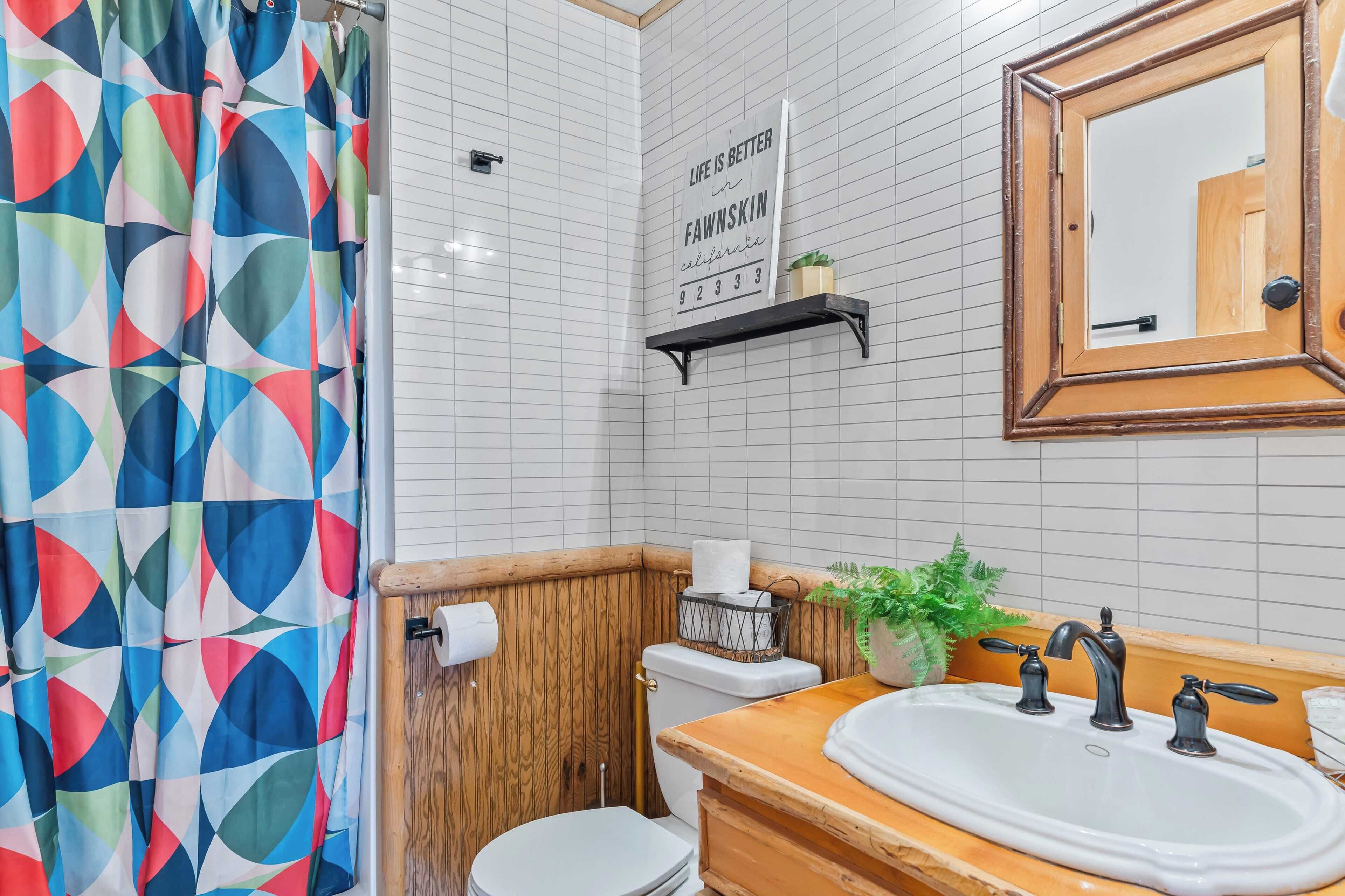Une salle de bain équipée d’un rideau de douche, de toilettes, d’un lavabo, d’un miroir et d’une citation inspirante sur le mur.