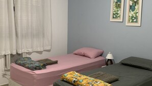 A bedroom with two beds, a ceiling fan, and two framed butterfly pictures on the wall.