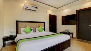 A hotel room with a bed, bedside table, and a TV mounted on the wall. - Treebo Trend Hotel NV (Narendranagar)