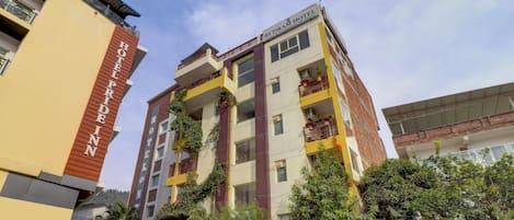 A multi-story hotel with a sign indicating it offers yoga and Ayurveda retreats.