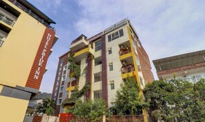 A multi-story hotel with a sign indicating it offers yoga and Ayurveda retreats. - Treebo Trend Hotel NV (Narendranagar)