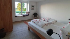 Een slaapkamer met een bed, een raam en een houten vloer.