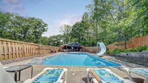 A swimming pool with lounge chairs, a slide, and a covered seating area. - BRAND NEW on VRBO Just A GEM W Hot Tub Seasonal HUGE POOL
  (Tafton)