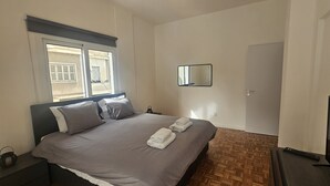 A bedroom with a bed, a nightstand, a window, a door, and a mirror. - 92 NIC - Stay Hydra Comfort Apartment (Nicosia)