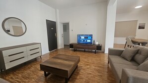 A modern living room with a wooden coffee table, a sofa, a TV on a stand, and a minimalist dresser. - 92 NIC - Stay Hydra Comfort Apartment (Nicosia)