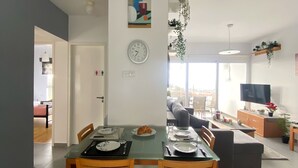 Un espace repas moderne avec une table en verre, des chaises en bois et une horloge au mur.