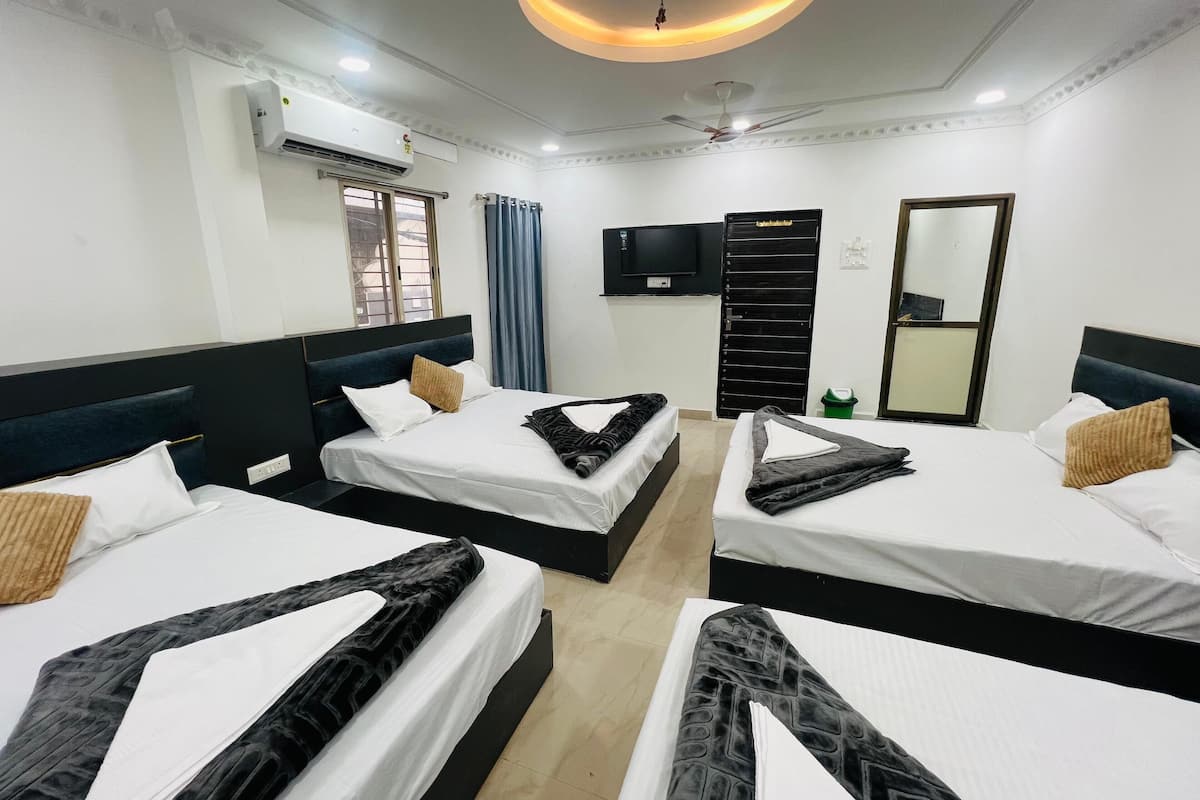 A hotel room with three beds, a flat-screen TV, an air conditioning unit, and a ceiling fan.