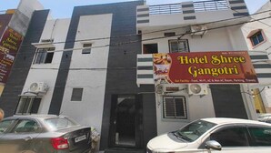 Un edificio con la insegna Hotel Shree Gangotri, che offre servizi come Wi-Fi, aria condizionata, camere con e senza aria condizionata, parcheggio e servizi di viaggio.