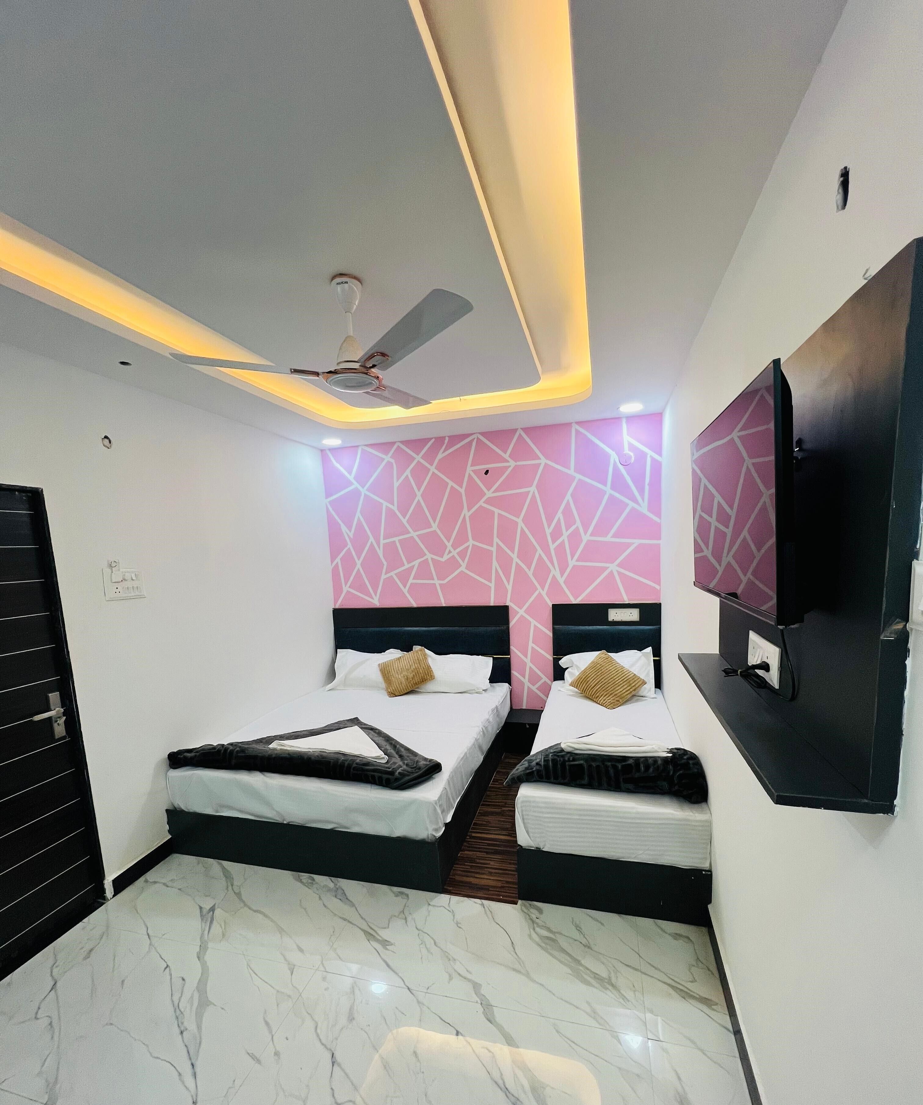 A hotel room with two beds, a ceiling fan, a TV mounted on the wall, and a marble floor.