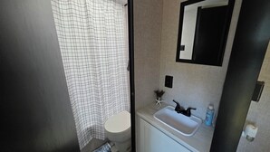 Une petite salle de bain comprenant des toilettes, un lavabo et un rideau de douche.