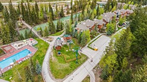 Vue aérienne d’un complexe touristique comprenant plusieurs chalets, une piscine et un télésiège.