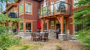 Une maison à plusieurs étages dotée d’un balcon, d’un espace salon extérieur et de détails en pierre.