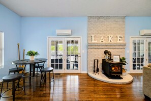 A room with a fireplace, a dining area with a table and chairs, and a wall with the word 'LAKE' spelled out in bricks. - Lakefront Retreat, Pool, Boat Dock, Hot Tub (Bumpass)