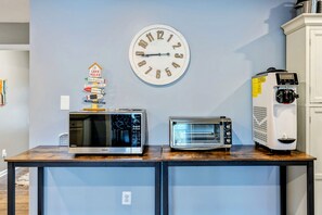A kitchen area with a microwave, toaster, and coffee maker on a wooden countertop. A wall clock is visible above the counter. - Lakefront Retreat, Pool, Boat Dock, Hot Tub (Bumpass)