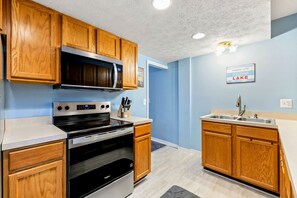 A kitchen with wooden cabinets, a microwave, an oven, and a sink. - Lakefront Retreat, Pool, Boat Dock, Hot Tub (Bumpass)