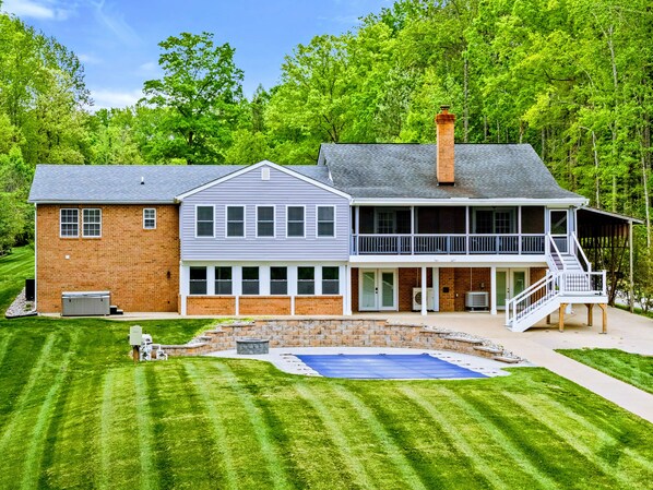 A two-story house with a large deck and a swimming pool.