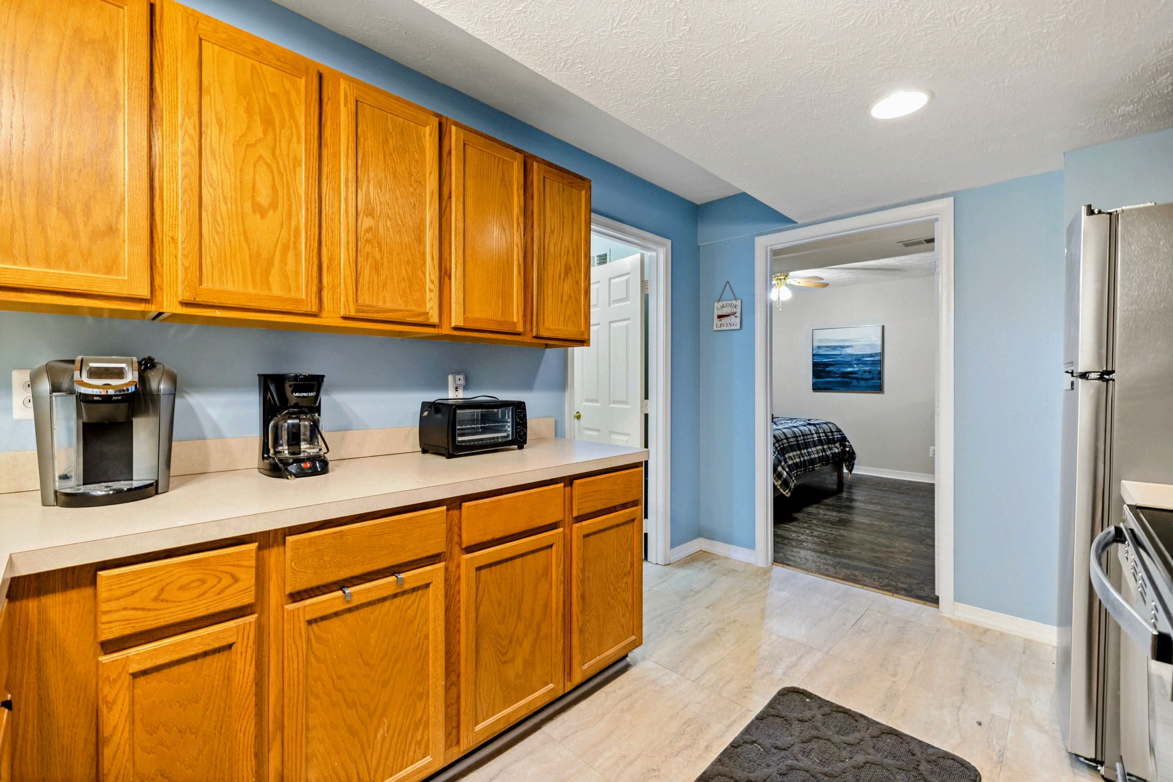 A kitchen with wooden cabinets, a coffee maker, a toaster, and a refrigerator.