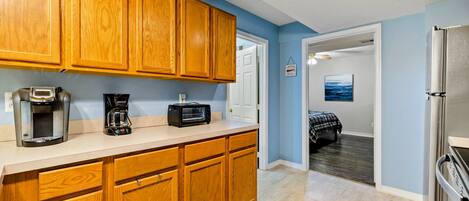 A kitchen with wooden cabinets, a coffee maker, a toaster, and a refrigerator.