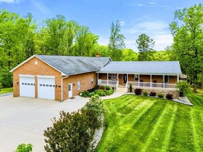 A two-story house with a garage, a covered porch, and a well-maintained lawn. - Lakefront Retreat, Pool, Boat Dock, Hot Tub (Bumpass)