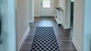 A hallway with a patterned rug, a white door, and a light fixture.